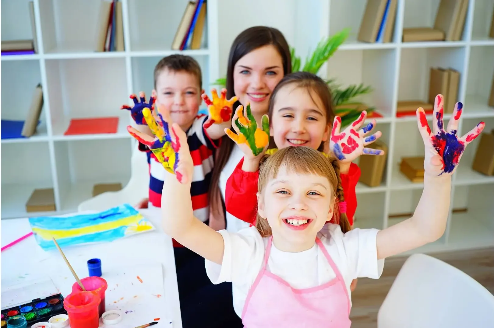 Childcare and education. Infant school. Children with paint on their hands with au-pair
